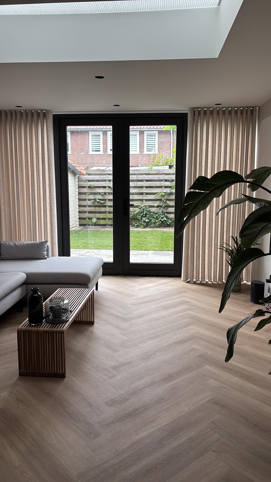 Woonkamer met visgraat vloer en zicht op de tuin